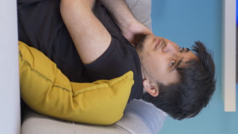 Vertical-video-of-Depressed-man-lying-on-the-sofa.